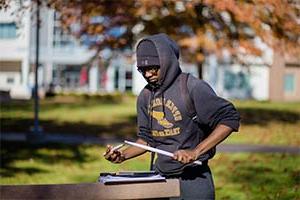 Student drumming on a notebook outside in the fall